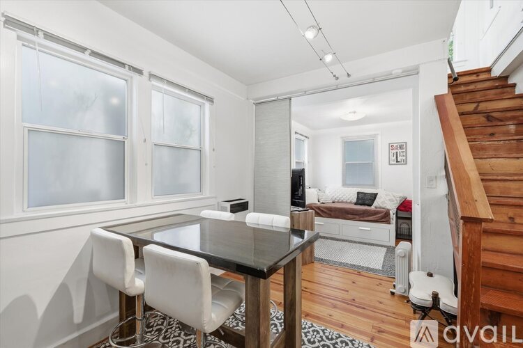 A dining area with a glass table and white chairs.