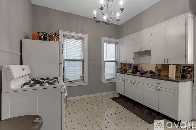 A kitchen with white cabinets and a tiled floor.