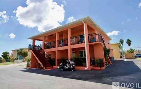 A two-story building with a balcony and a motorcycle parked in front.