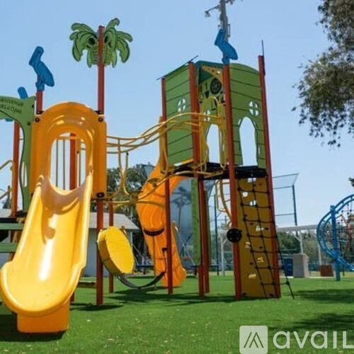 A playground with a yellow slide and a green tower.