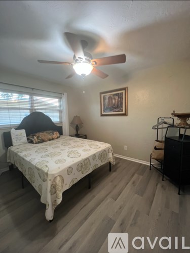 A bedroom with a bed, a ceiling fan, and a chair.