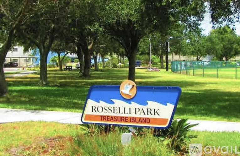 A sign for Rosselli Park Treasure Island sits in front of a green fence.