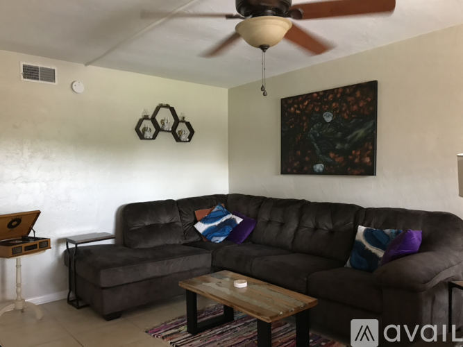 A living room with a brown couch and a ceiling fan.