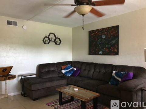 A living room with a brown couch and a ceiling fan.