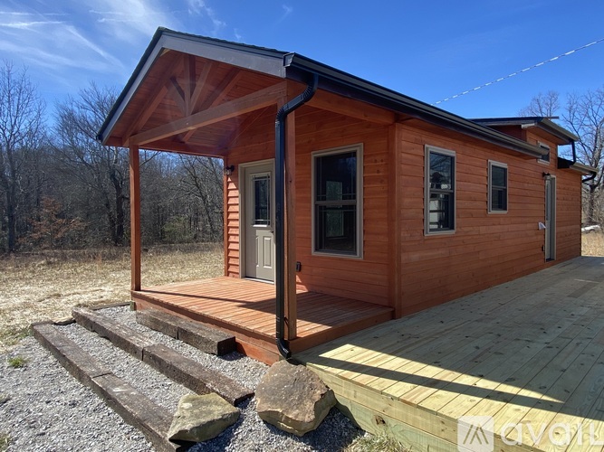 A wooden cabin with a porch and a covered entrance.