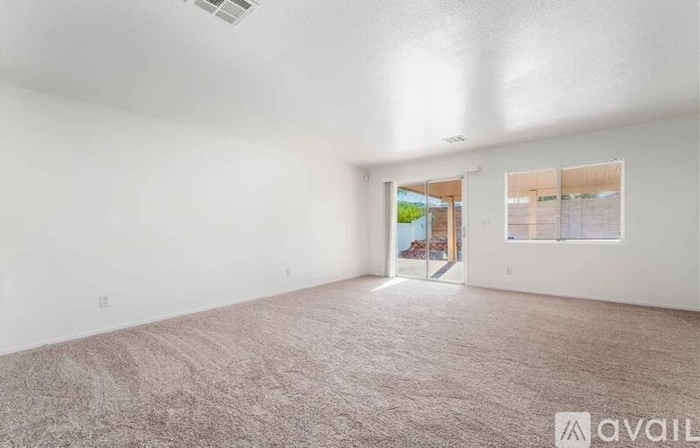 A spacious room with a carpeted floor and a ceiling fan.