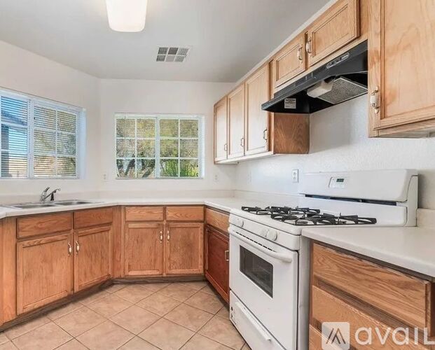 A kitchen with wooden cabinets and a white stove top oven.