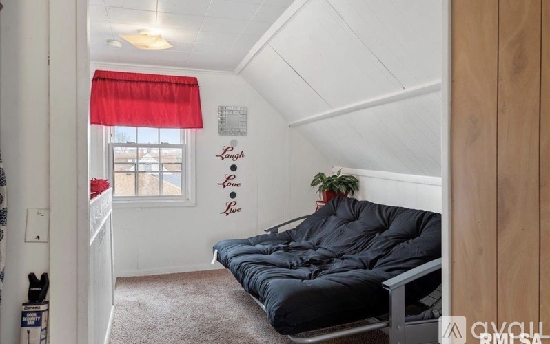 A bedroom with a bed and a window with red curtains.