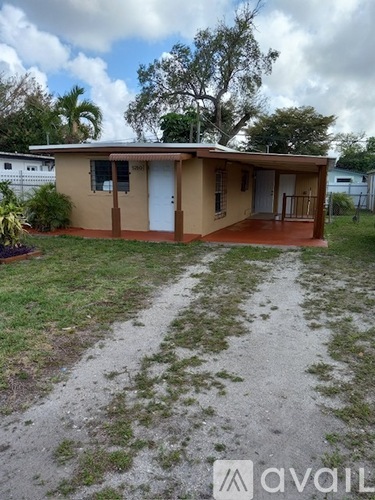 A house with a brown and beige exterior is surrounded by a grassy area and a dirt path.