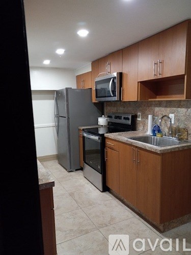 A kitchen with brown cabinets and a black refrigerator.