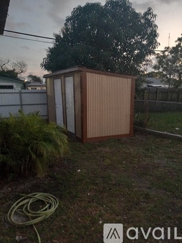 A brown shed sits in a yard with a hose on the ground.