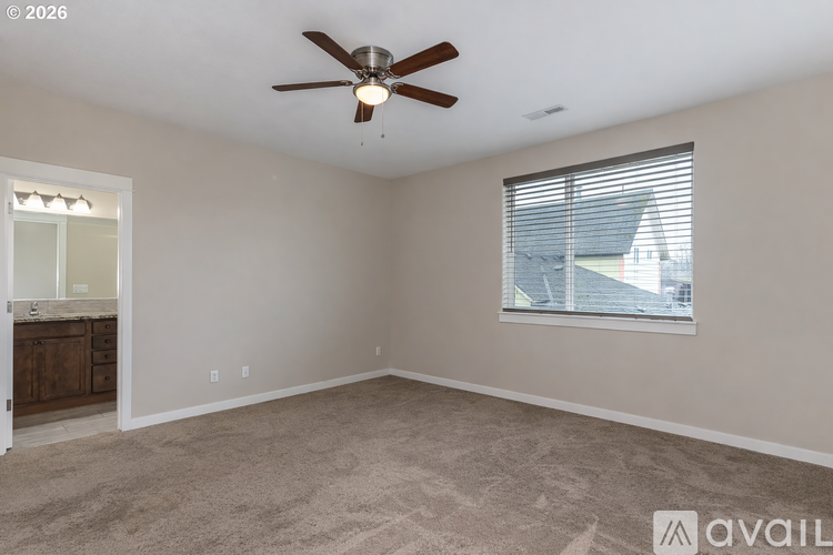 A spacious room with a ceiling fan and a window with blinds.