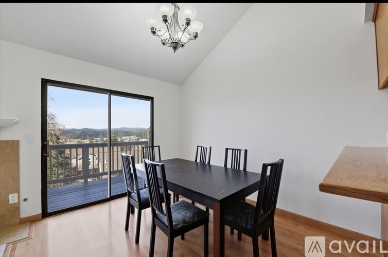 A dining room with a table and chairs and a balcony outside.