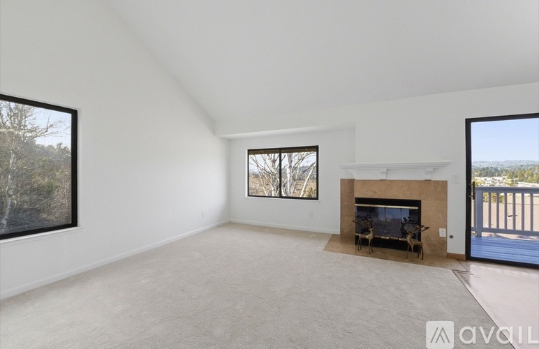 A spacious living room with a fireplace and large windows.