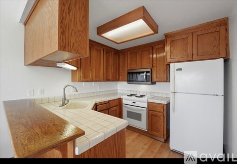 A kitchen with wooden cabinets and a white refrigerator.