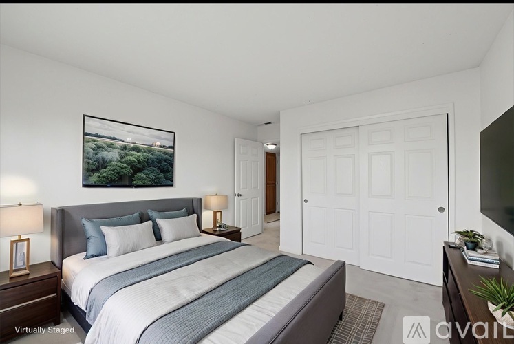 A bedroom with a large bed and a painting on the wall.