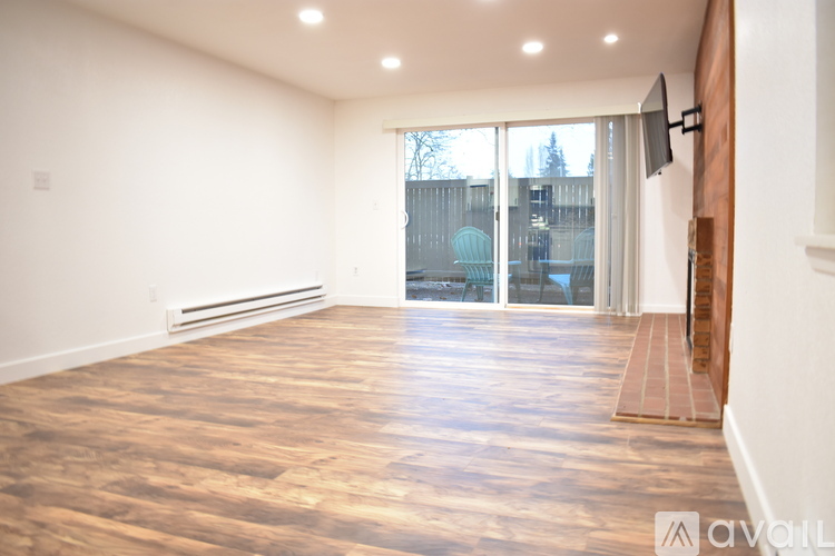 A spacious room with wooden flooring and a large window.