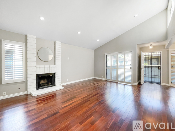 A spacious room with a fireplace and wood flooring.