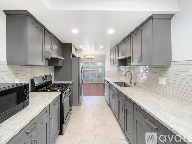 A kitchen with a white counter top and grey cabinets.