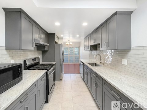 A kitchen with a white counter top and grey cabinets.