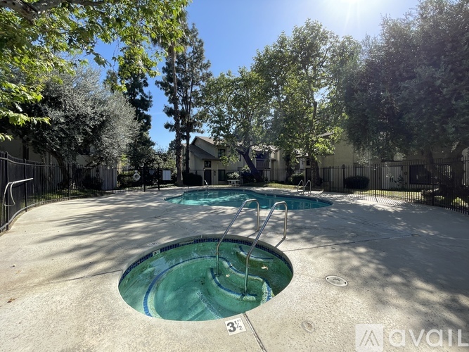 A swimming pool surrounded by trees and a fence.