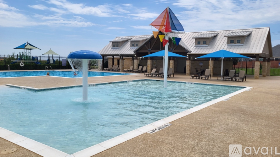 A large outdoor swimming pool with a blue umbrella and a white pole in the middle.