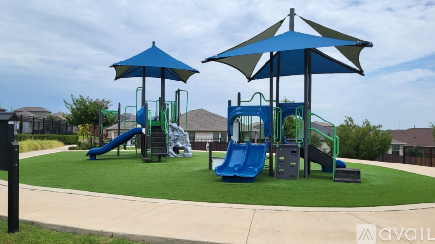 A playground with a blue slide and two blue umbrellas.
