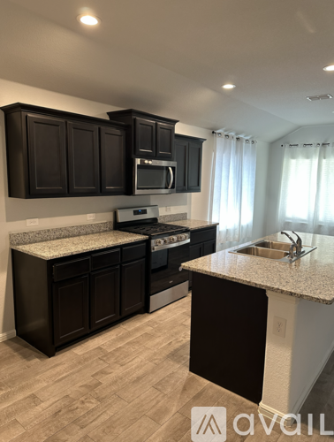A kitchen with dark brown cabinets and a granite countertop.