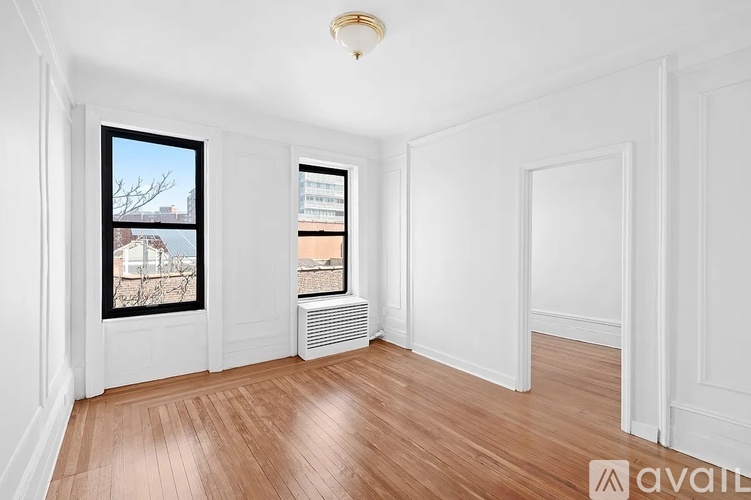 A room with wooden floors and white walls, with a window showing a snowy scene outside.
