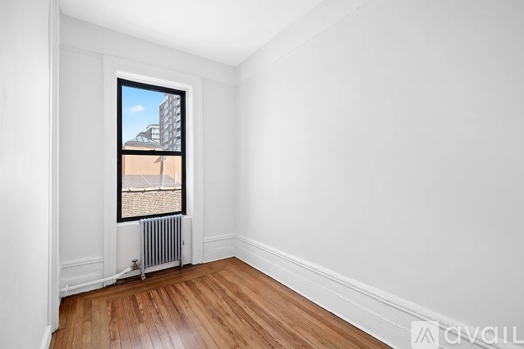 A room with a window and a radiator on the floor.