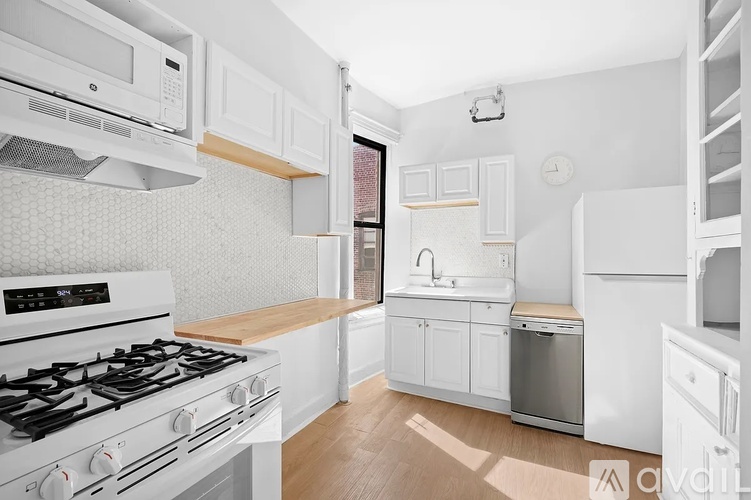 A white kitchen with a stove top oven and a microwave above it.