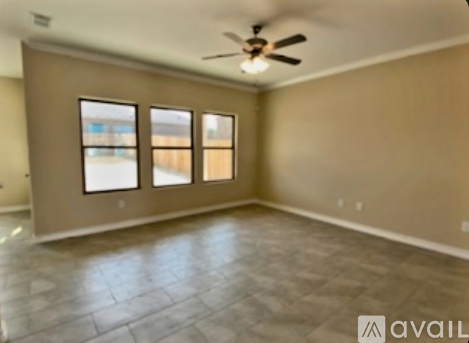 A spacious room with a ceiling fan and large windows.