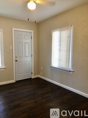 A room with a door, a window with blinds, and a ceiling fan.