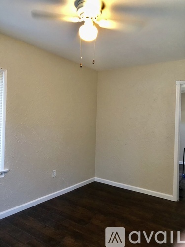 A room with a ceiling fan and wooden flooring.