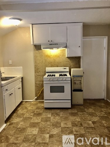 A kitchen with a white stove and oven, and a white dishwasher.