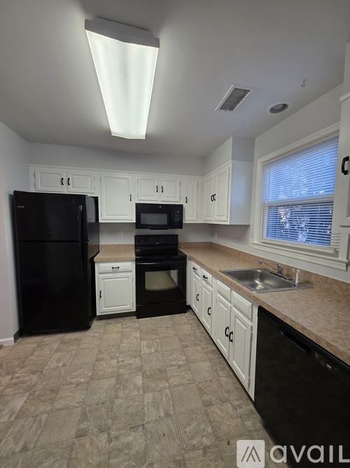 A kitchen with black appliances and white cabinets.