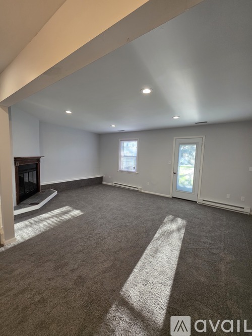 A spacious living room with a fireplace and a carpeted floor.