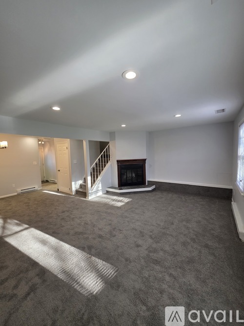 A spacious living room with a fireplace and a carpeted floor.