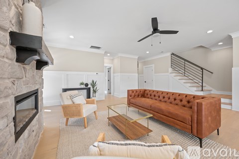 A living room with a brown couch and a stone fireplace.