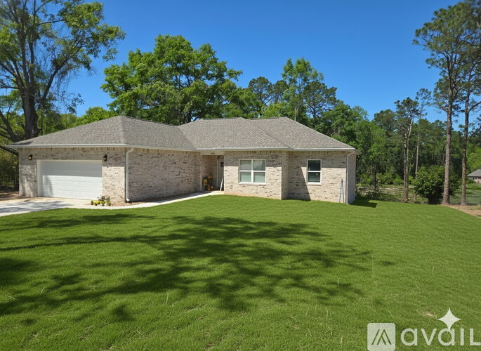 A house with a large lawn and trees in the background.