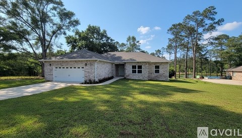 A house with a large lawn and trees in the background.