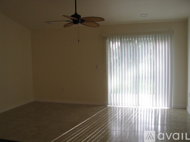 A room with a ceiling fan and a window with blinds.