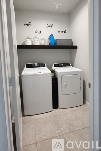 A laundry room with two washing machines and a shelf with laundry products.