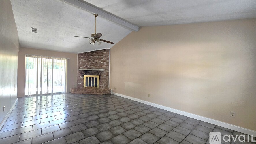 A room with a stone fireplace and a ceiling fan.