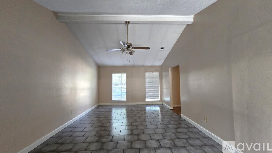 A spacious room with a ceiling fan and tiled floor.