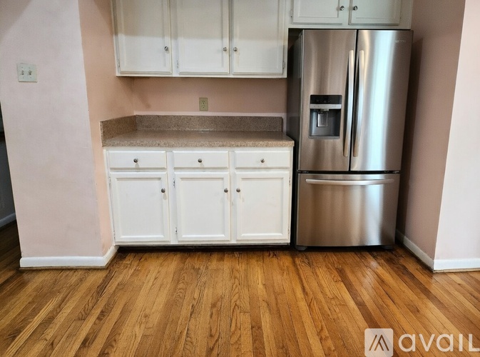A kitchen with a stainless steel refrigerator and white cabinets.