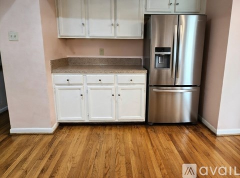 A kitchen with a stainless steel refrigerator and white cabinets.