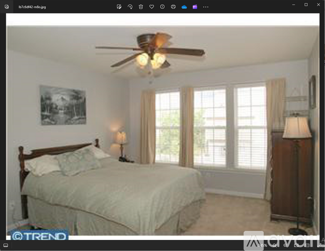A bedroom with a bed, a ceiling fan, and a window with blinds.