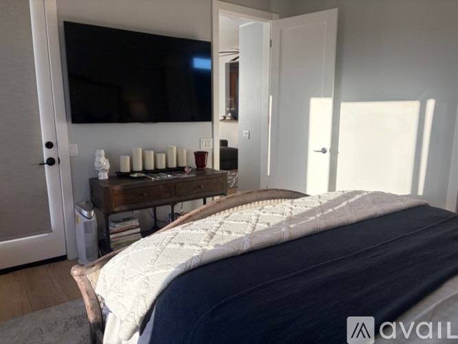 A bedroom with a bed, a TV, and a dresser with a mirror.