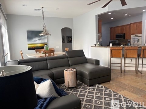 A modern living room with a grey sofa and a black ottoman.